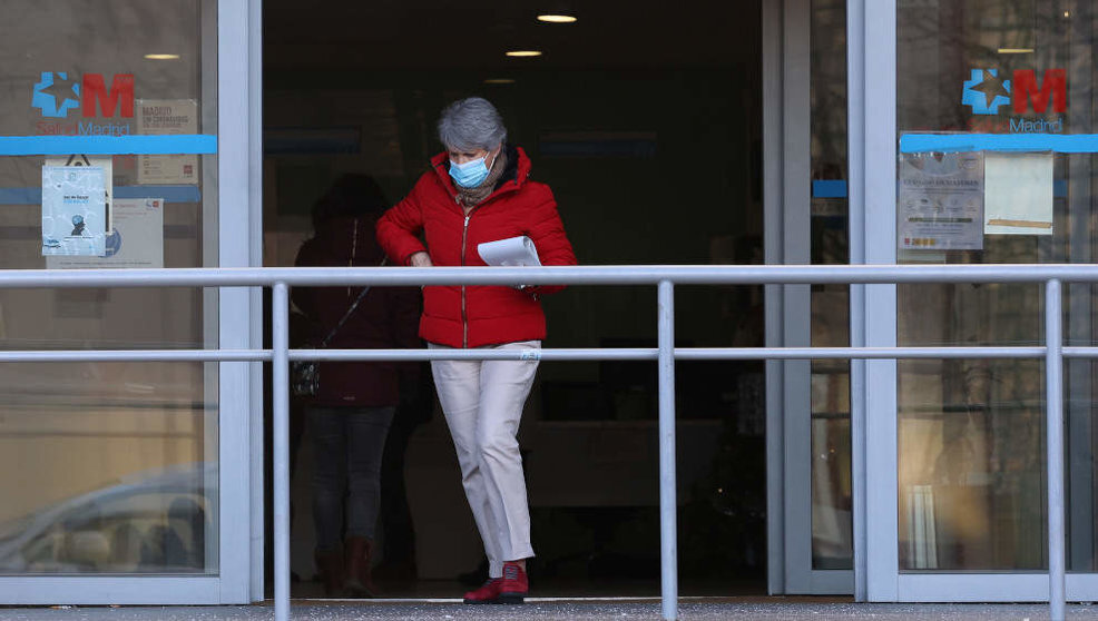 Una señora sale de un centro de salud con mascarilla