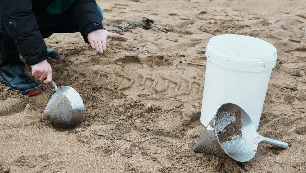 Un voluntario recoge pellets en la playa