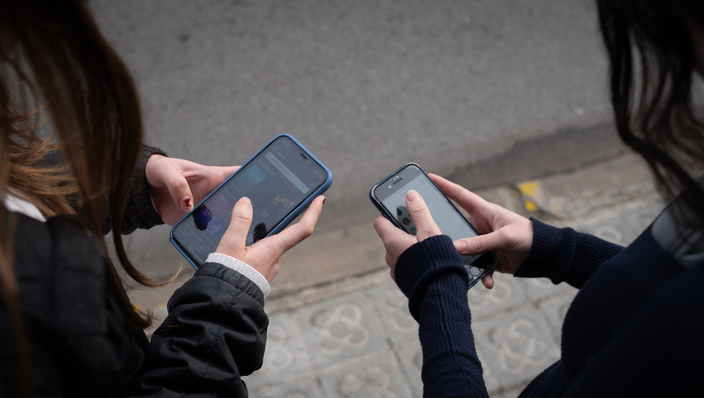 Dos jóvenes usan el teléfono móvil