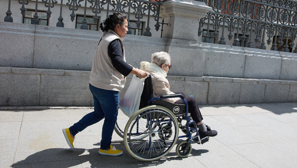 Mujer mayor en silla de ruedas y su cuidadora paseando